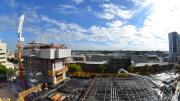 "Steel mesh laid on black flooring, concrete arm delivers wet concrete to be laid." 
